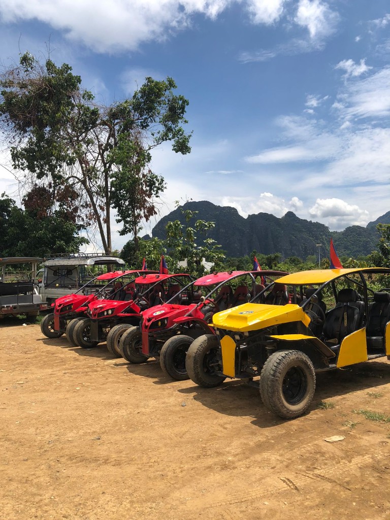 Red and yellow rental buggies lined up with Vang Vieng mountains in the background